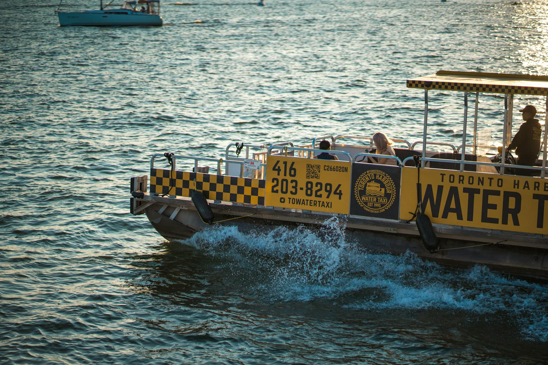 Small colorful water taxi crossing an urban harbour with city buildings behind