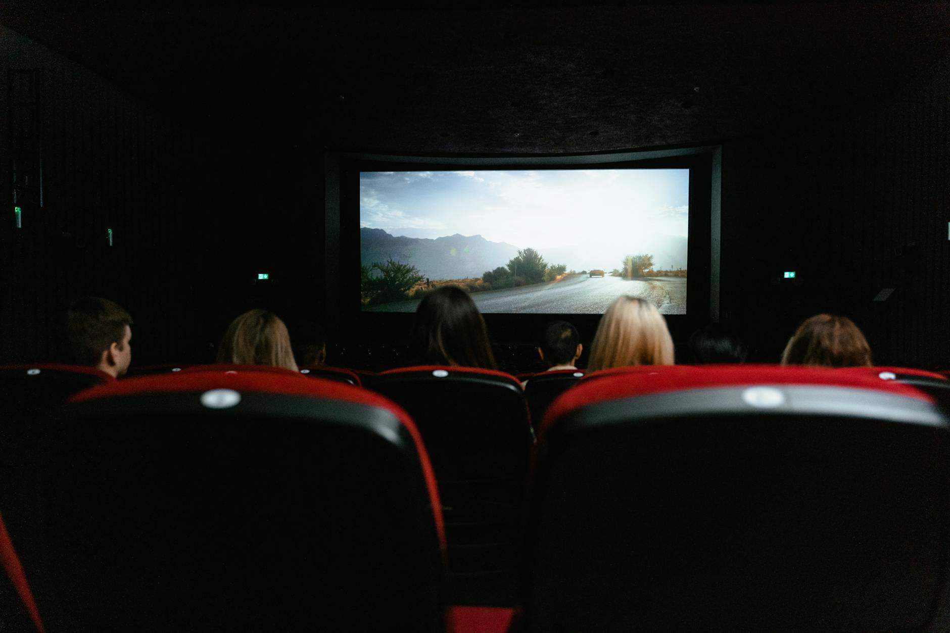 Empty cinema theatre with rows of red seats facing the screen