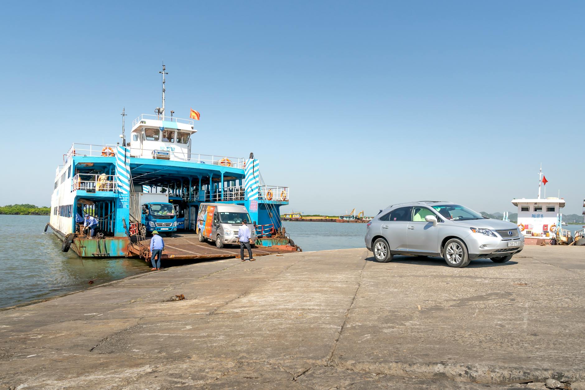 Large car ferry docked at a terminal loading vehicles and passengers