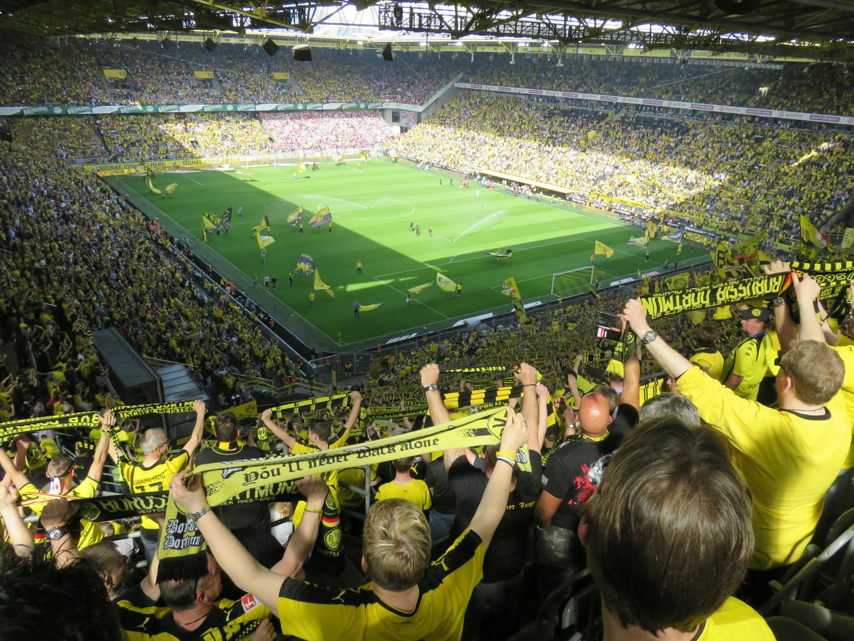 Soccer stadium interior packed with fans holding flags during a night match