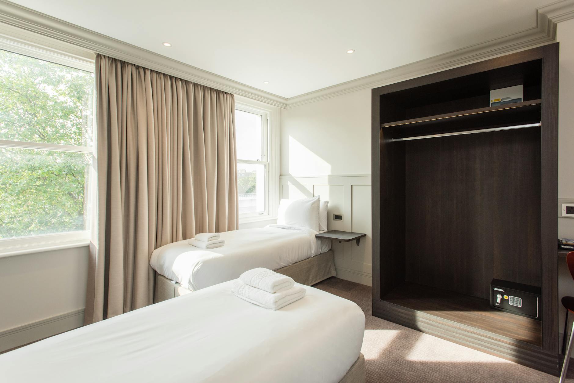 Clean minimal budget hotel room with twin beds and neutral wall colour
