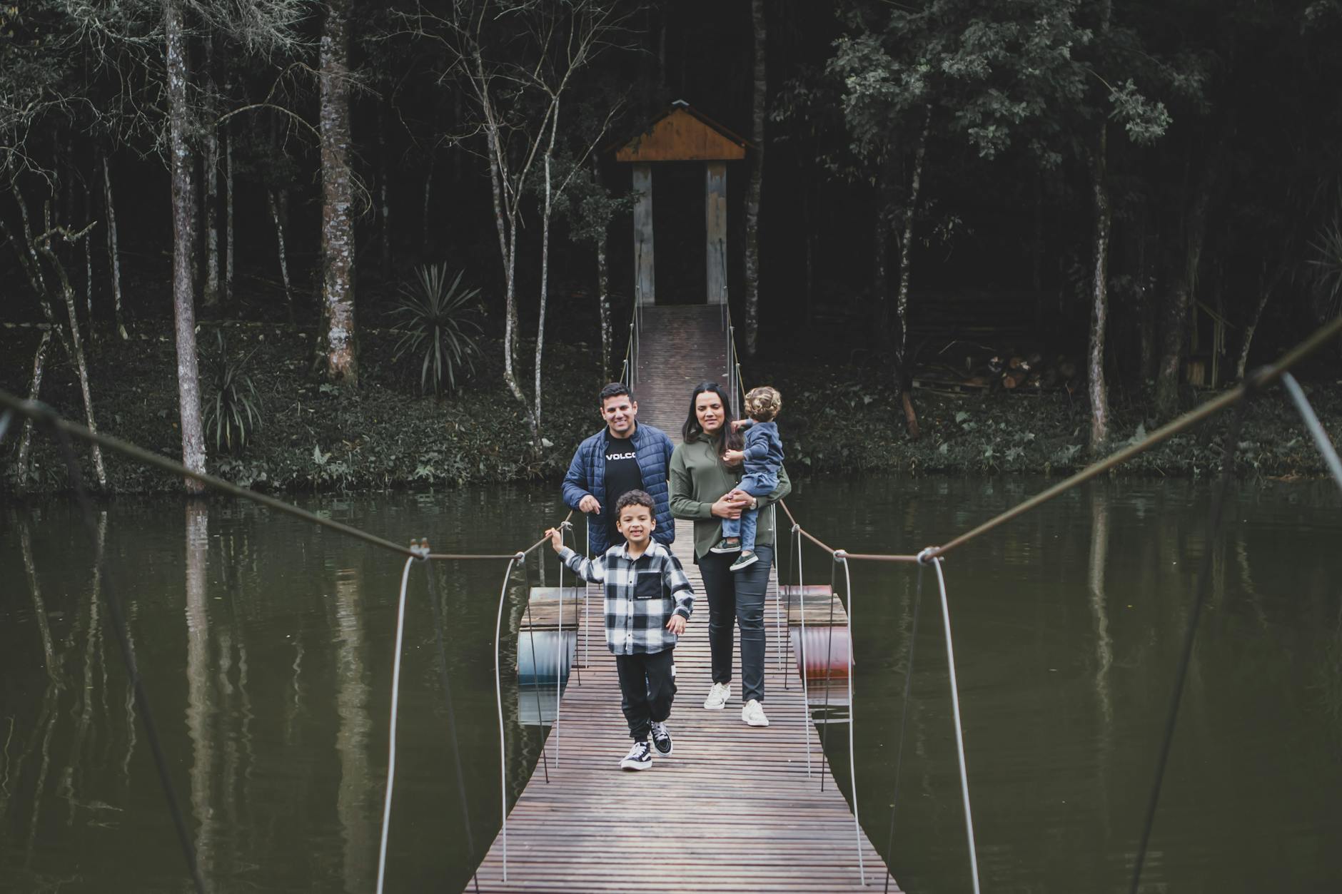 Family crossing suspension bridge in forest