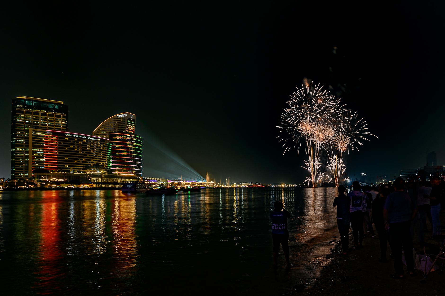Fireworks over water with crowd watching