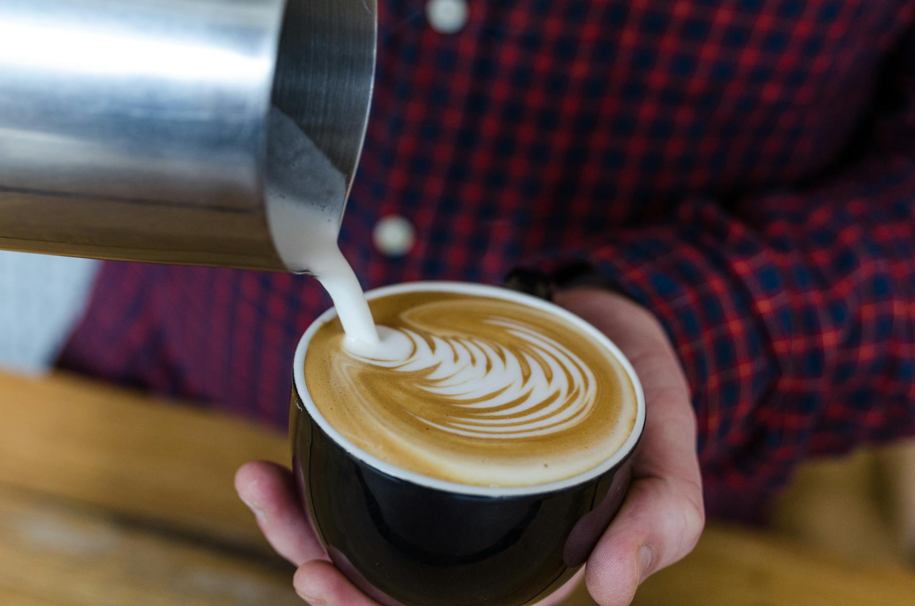 Barista pouring latte art in specialty coffee shop