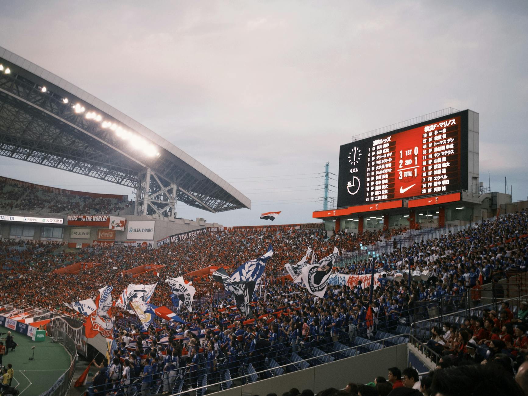 Soccer stadium packed with fans waving flags during an evening match