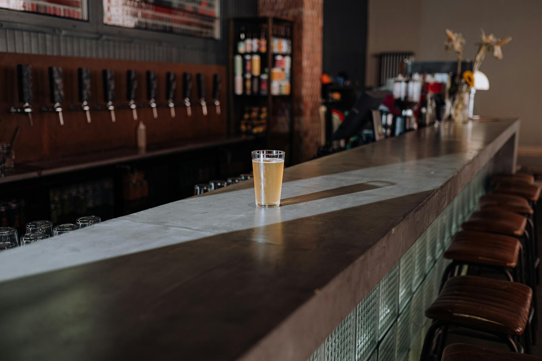 Industrial craft brewery taproom with stainless fermenters and wooden bar