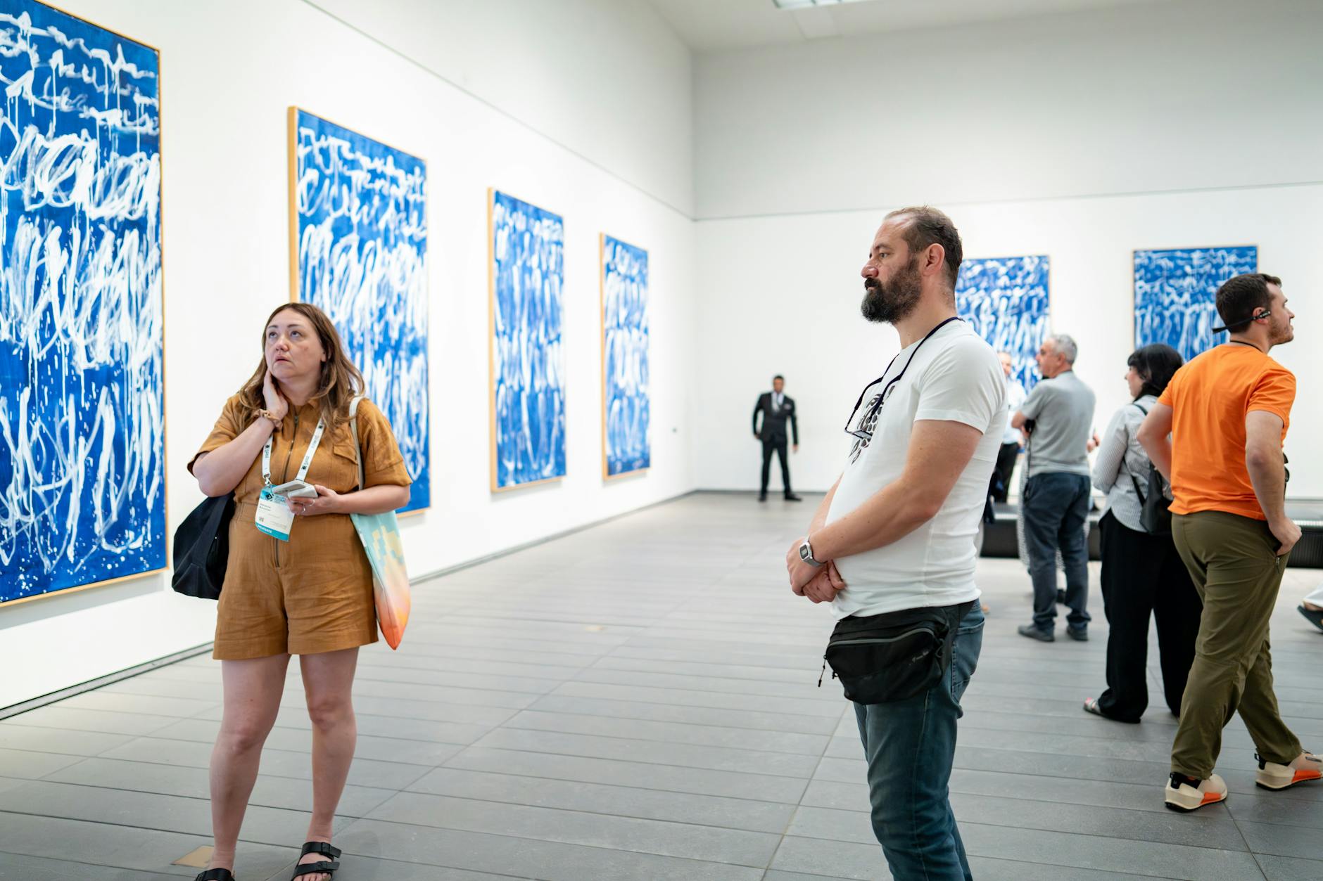 Gallery interior with paintings and visitors