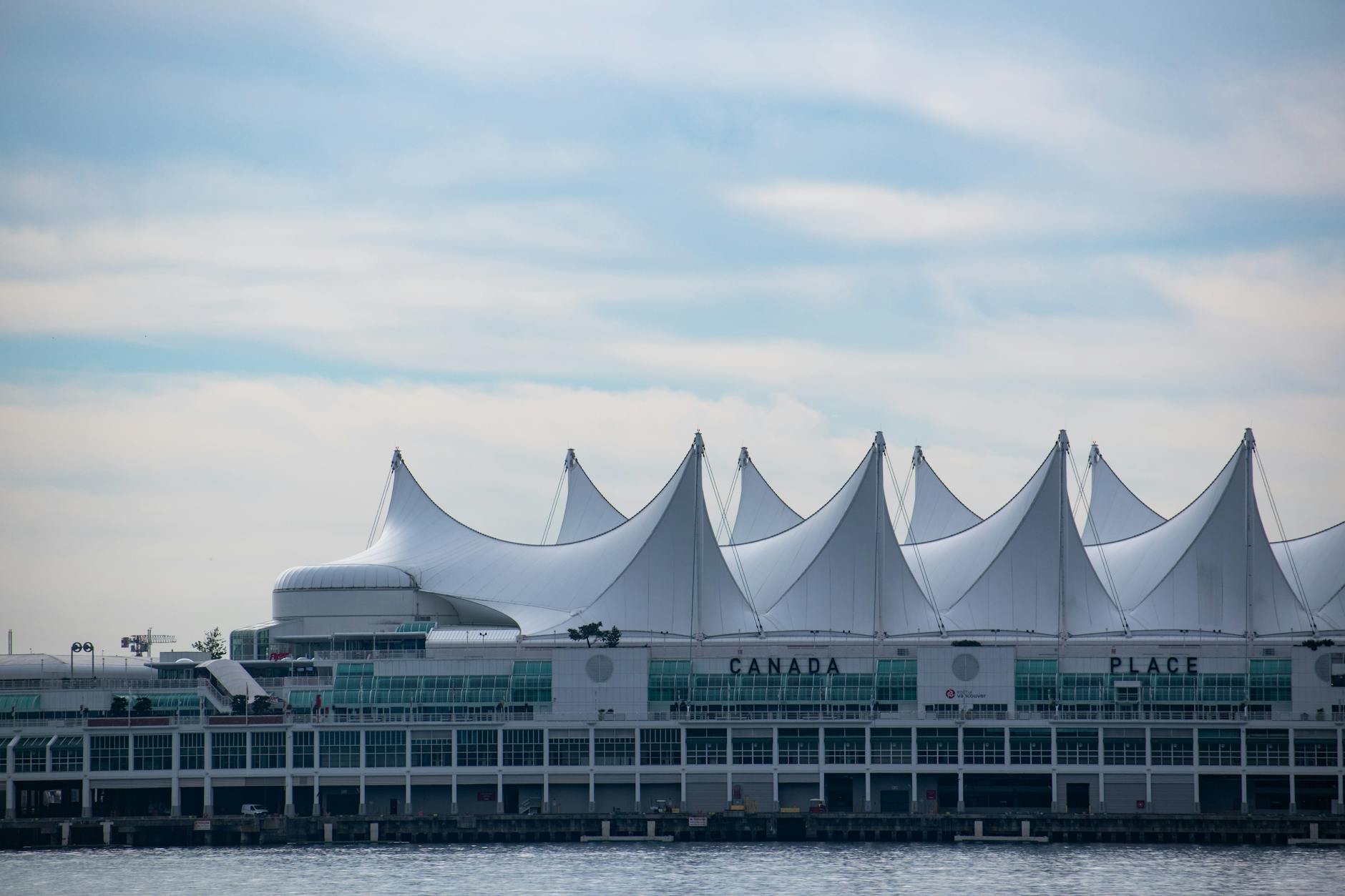 Iconic Canada Place building with its sail-like roof in Vancouver, BC against a blue sky.