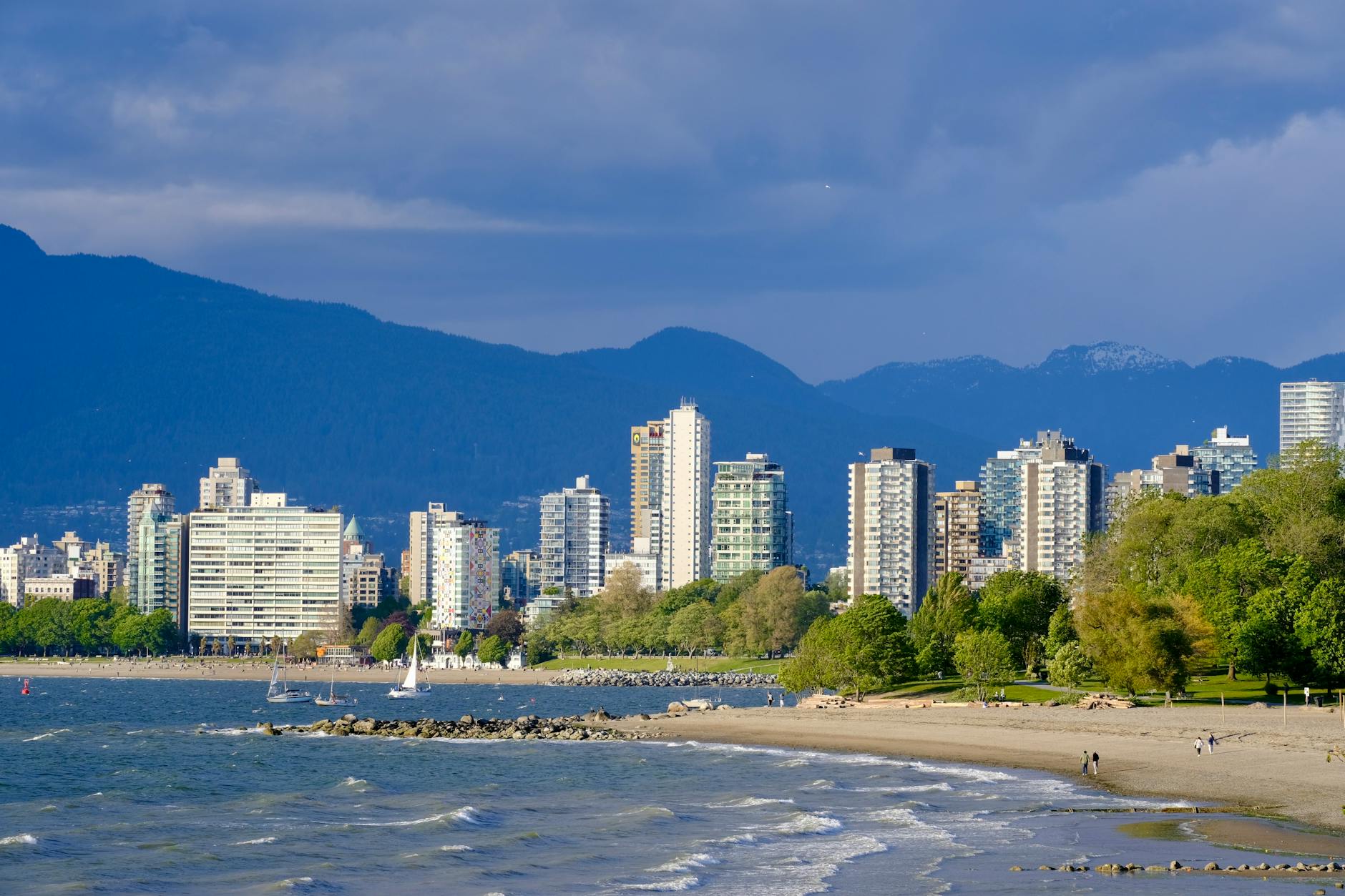 Vancouver's skyline from the beach with water and mountains in view.