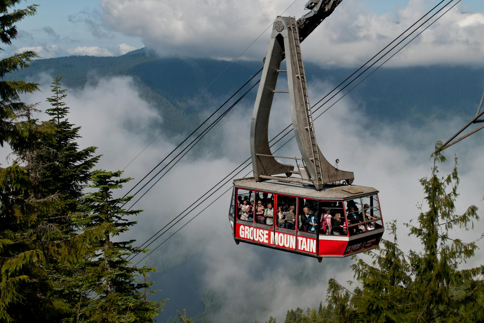 Stunning view of a cable car ascending Grouse Mountain in North Vancouver amidst lush greenery and fog.