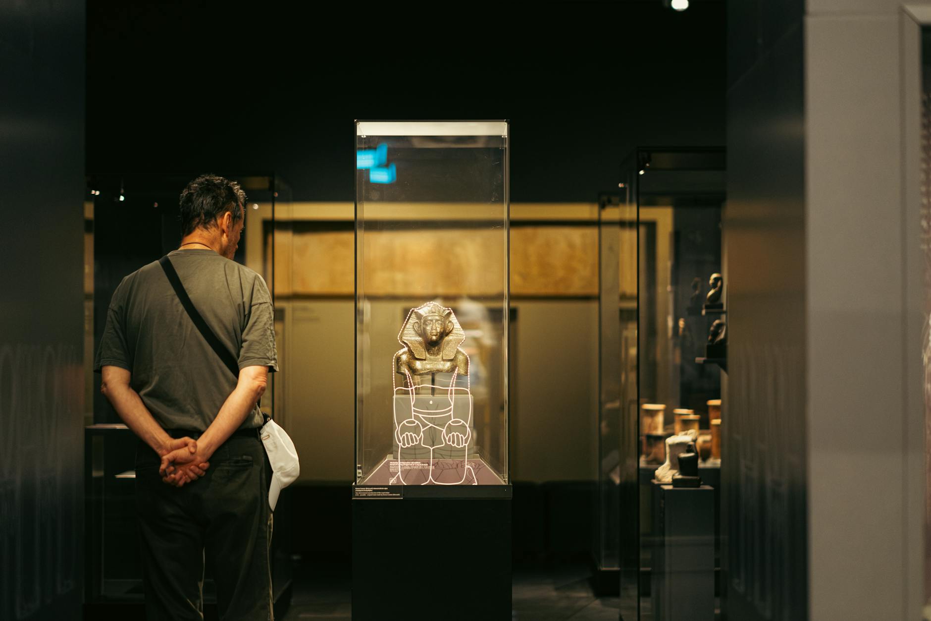 Visitor observing an ancient Egyptian artifact display in a Budapest museum exhibit.