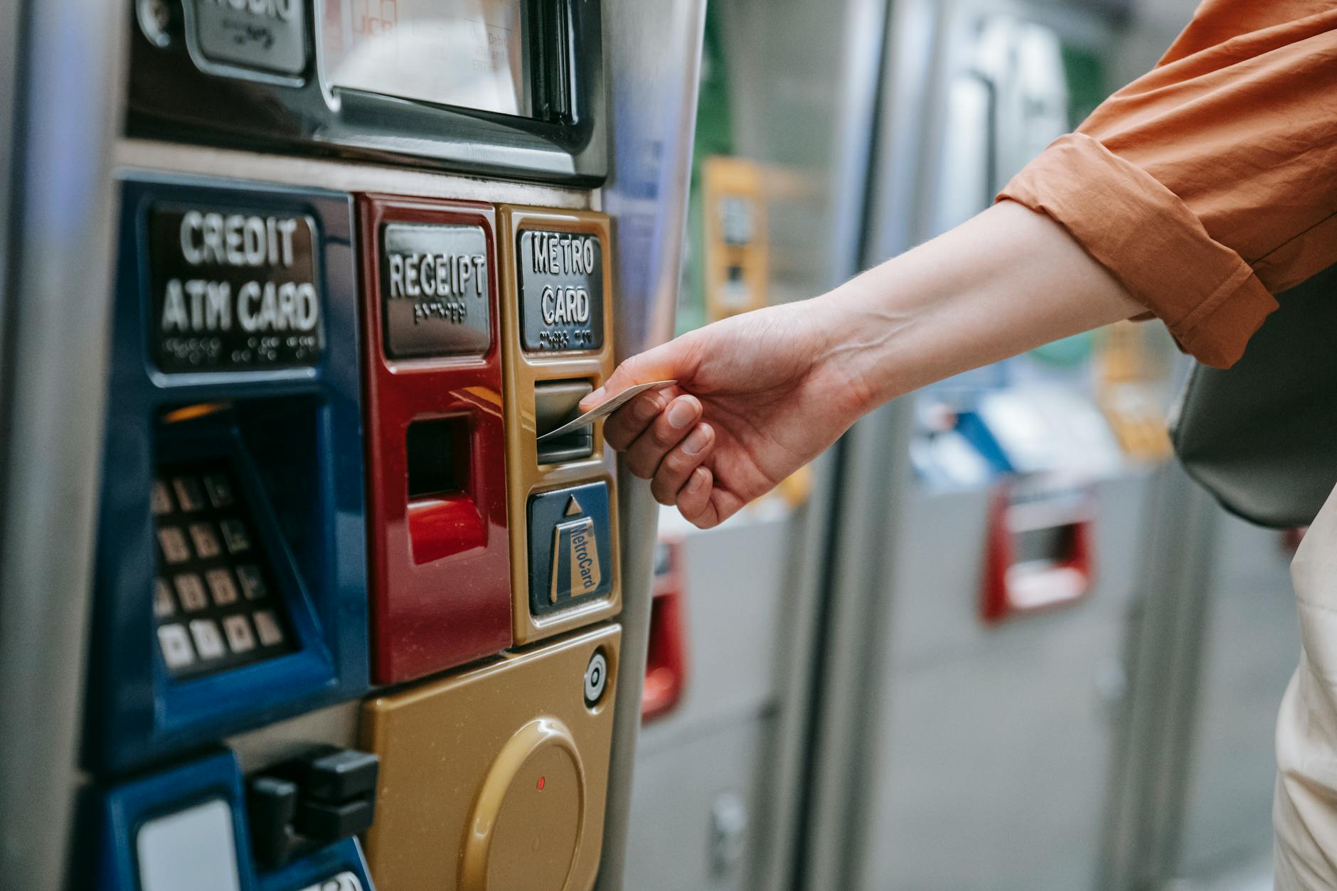 Close-up of a person using a metro card machine for public transport payment indoors.