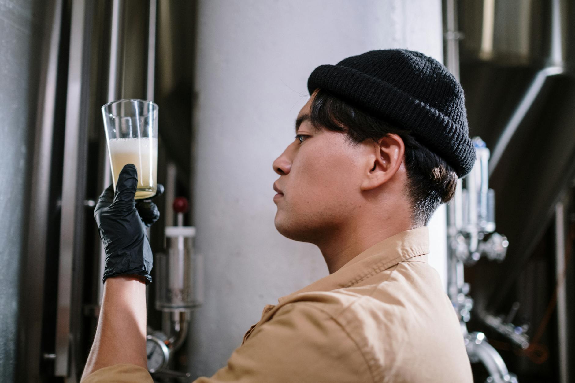 A brewmaster inspects craft beer in a glass, focusing on quality control in the brewery.