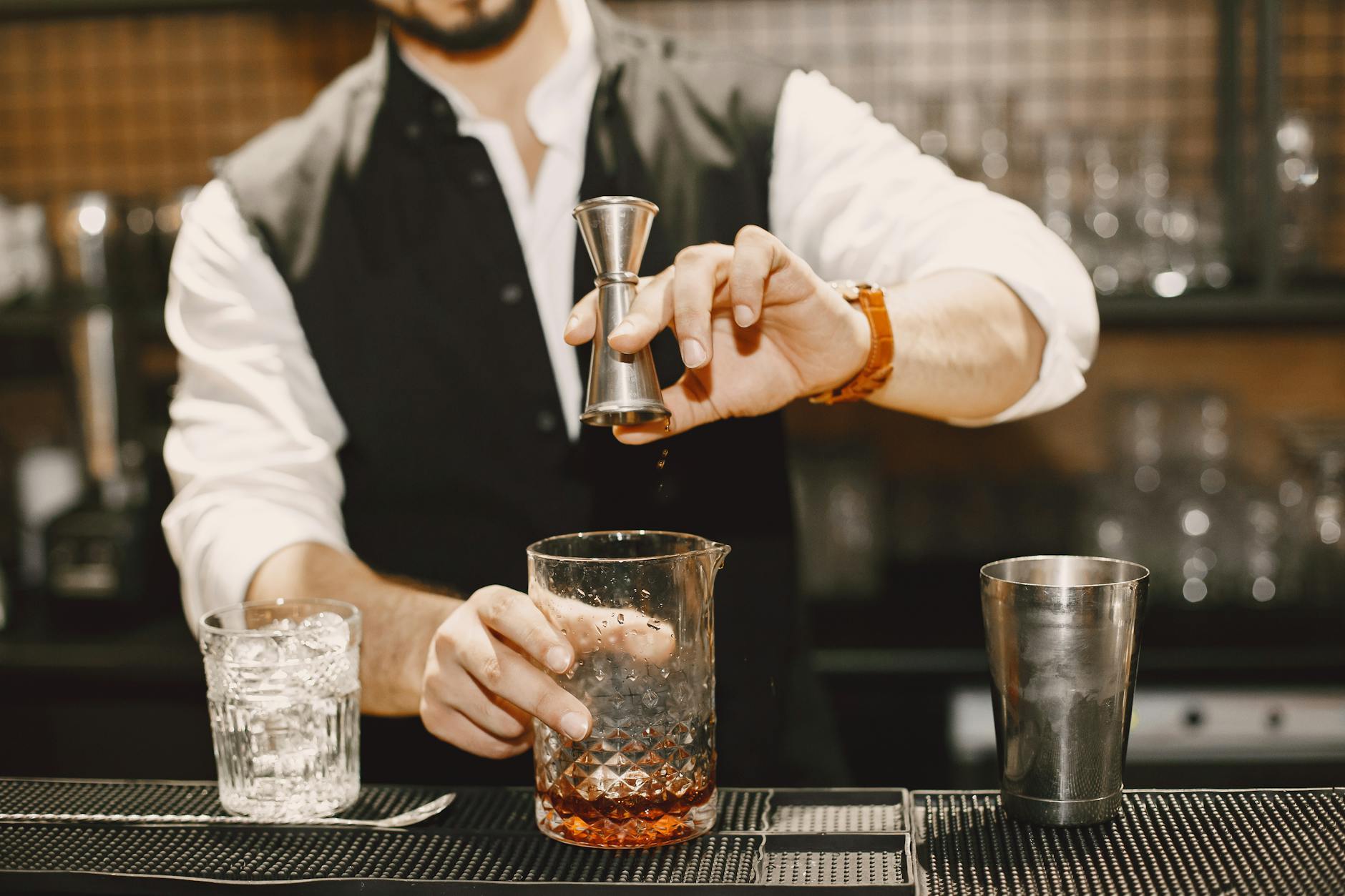 Cocktails garnished with citrus and herbs on a dark bar top.
