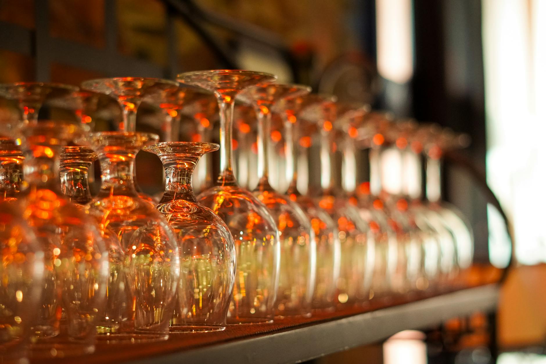 Glasses of red and white wine lined up on a bar counter.