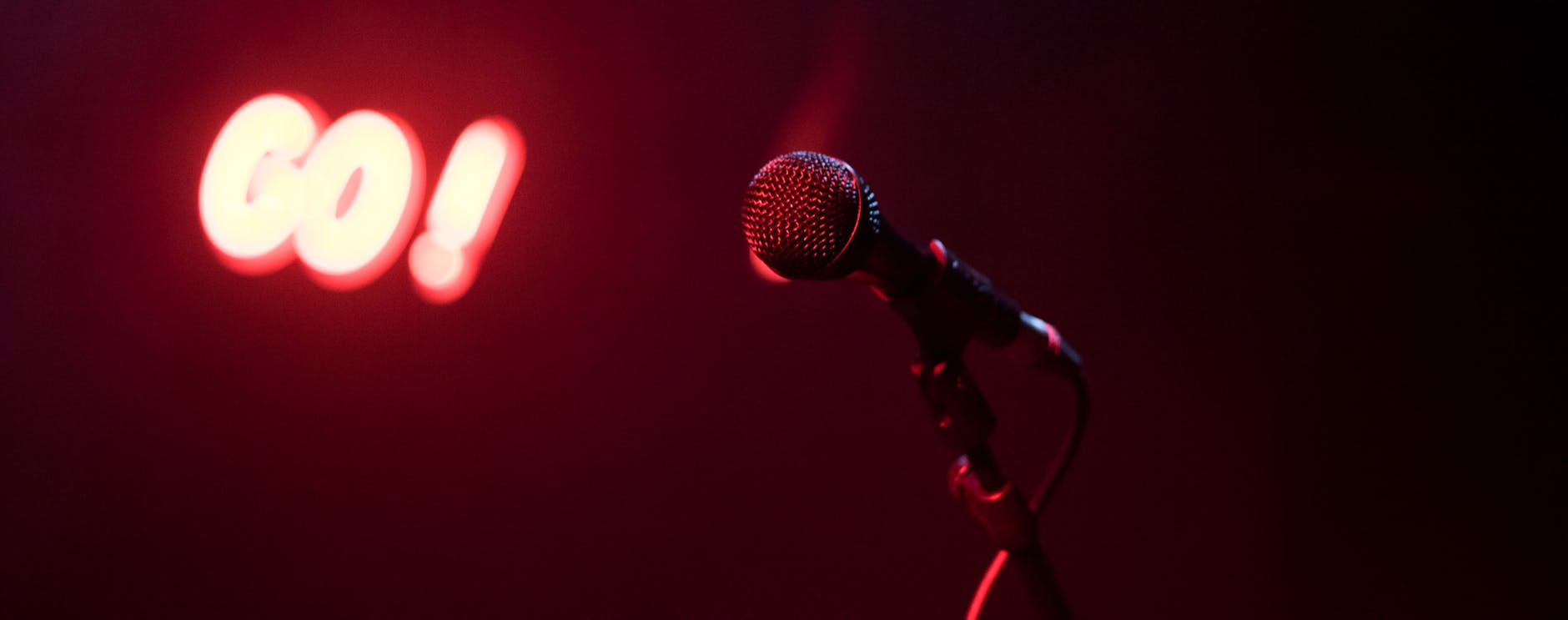 A comedian on stage with a microphone under a spotlight.