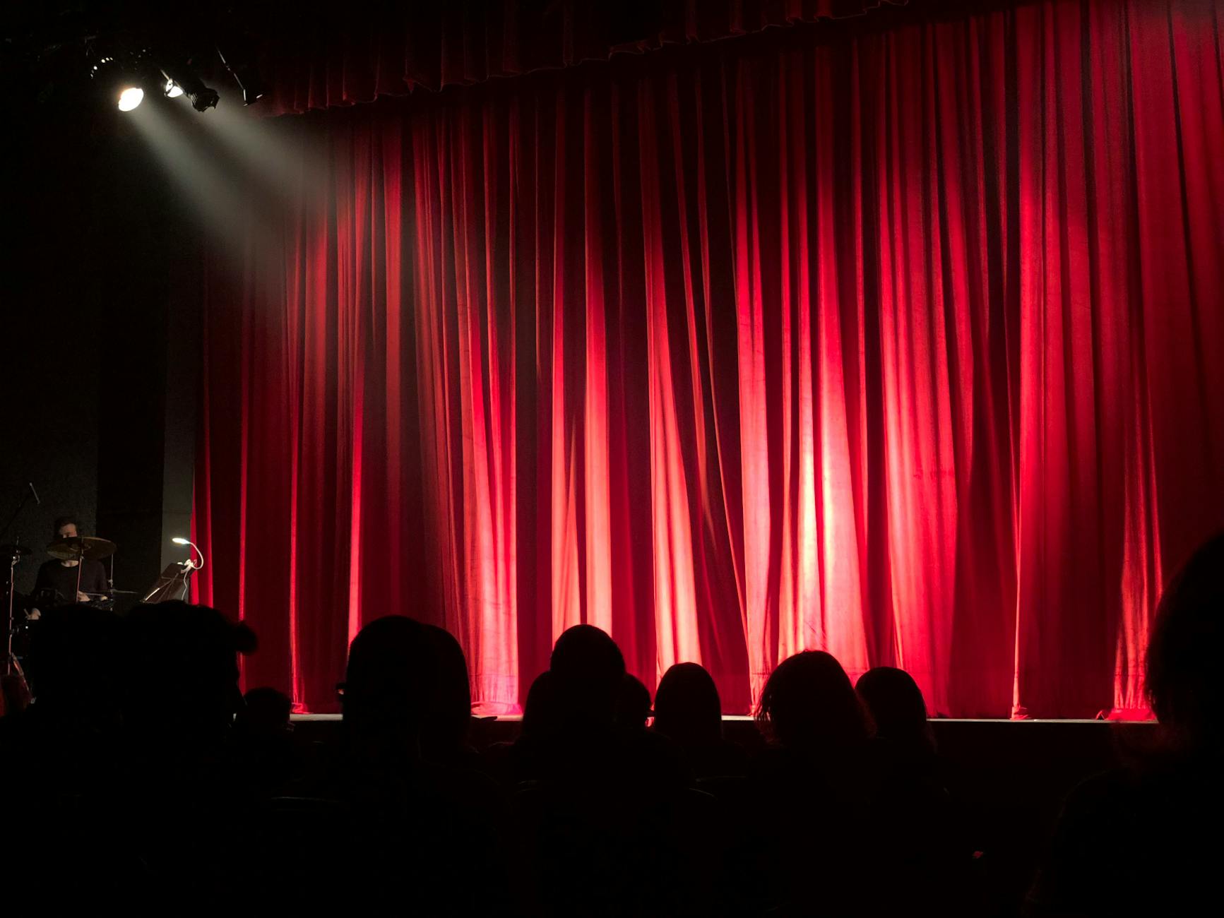 A microphone stand on an empty comedy club stage with a brick backdrop.