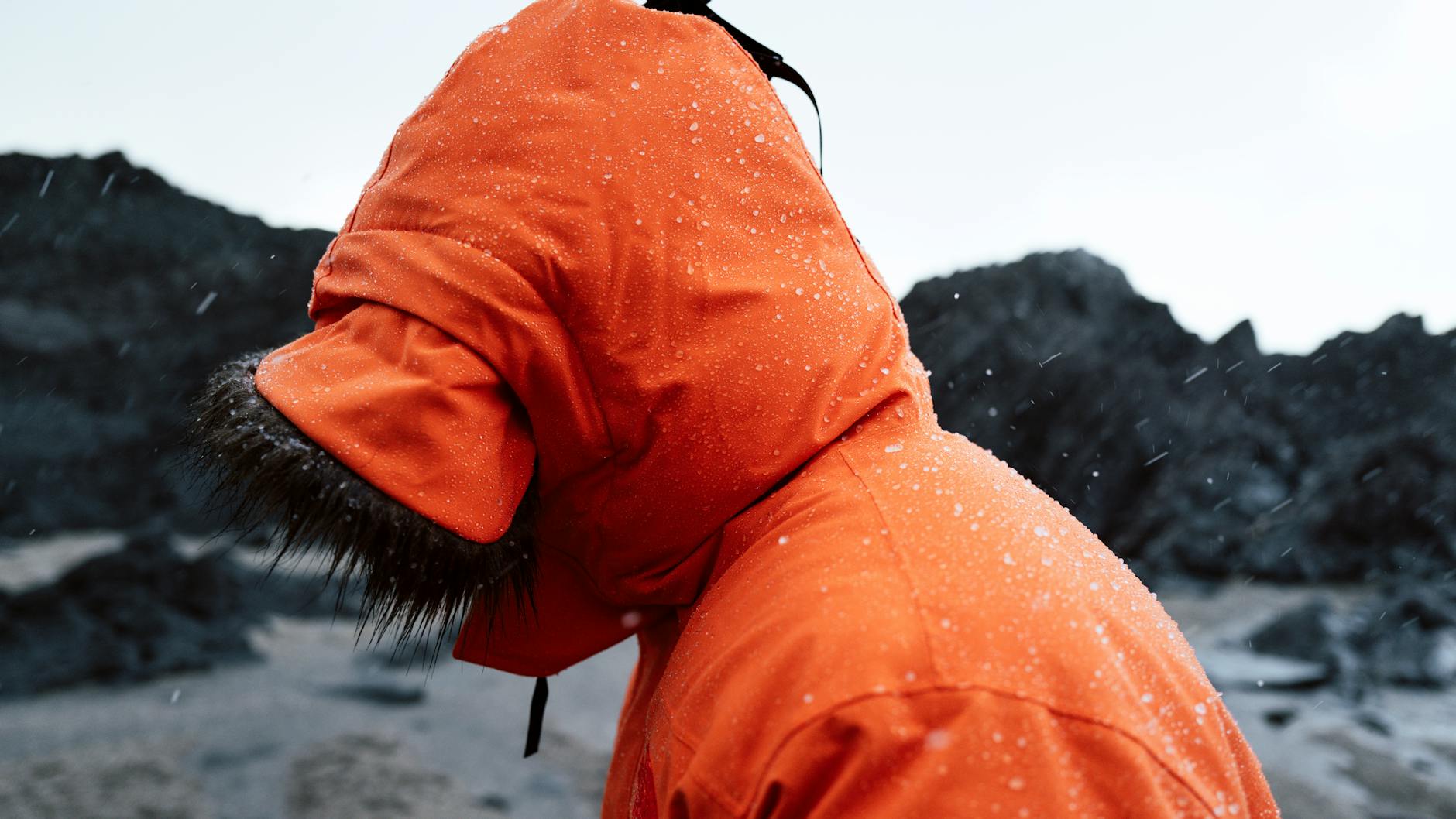 A waterproof rain jacket and boots laid out for winter travel.