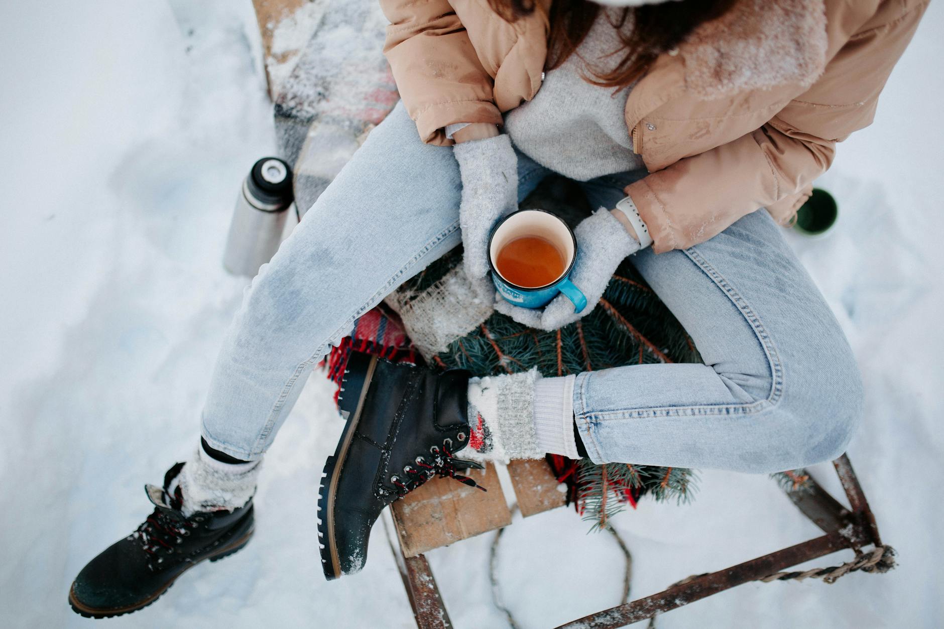 A packed travel bag with winter clothing and boots.