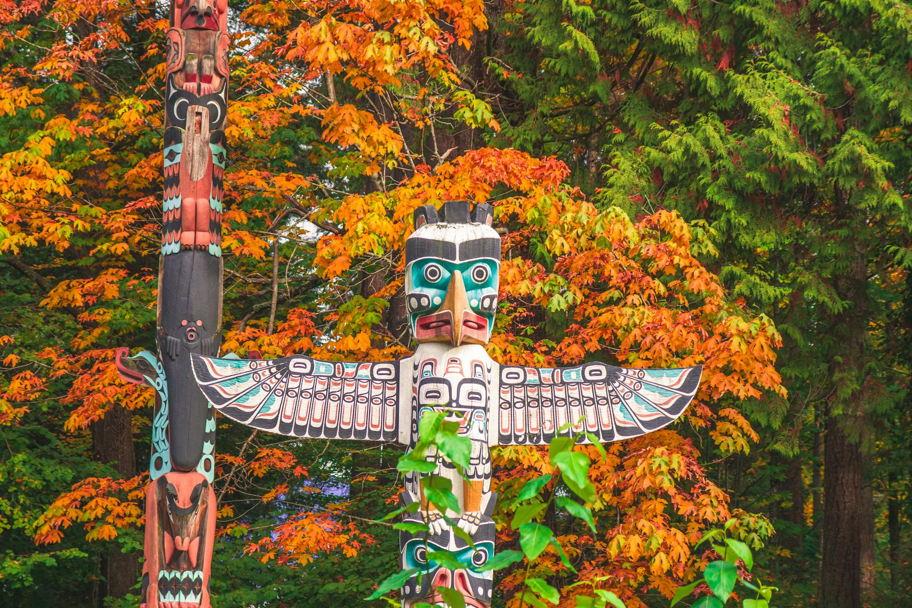 Vibrant totem pole amidst autumn foliage in Vancouver, Canada, showcasing indigenous art.