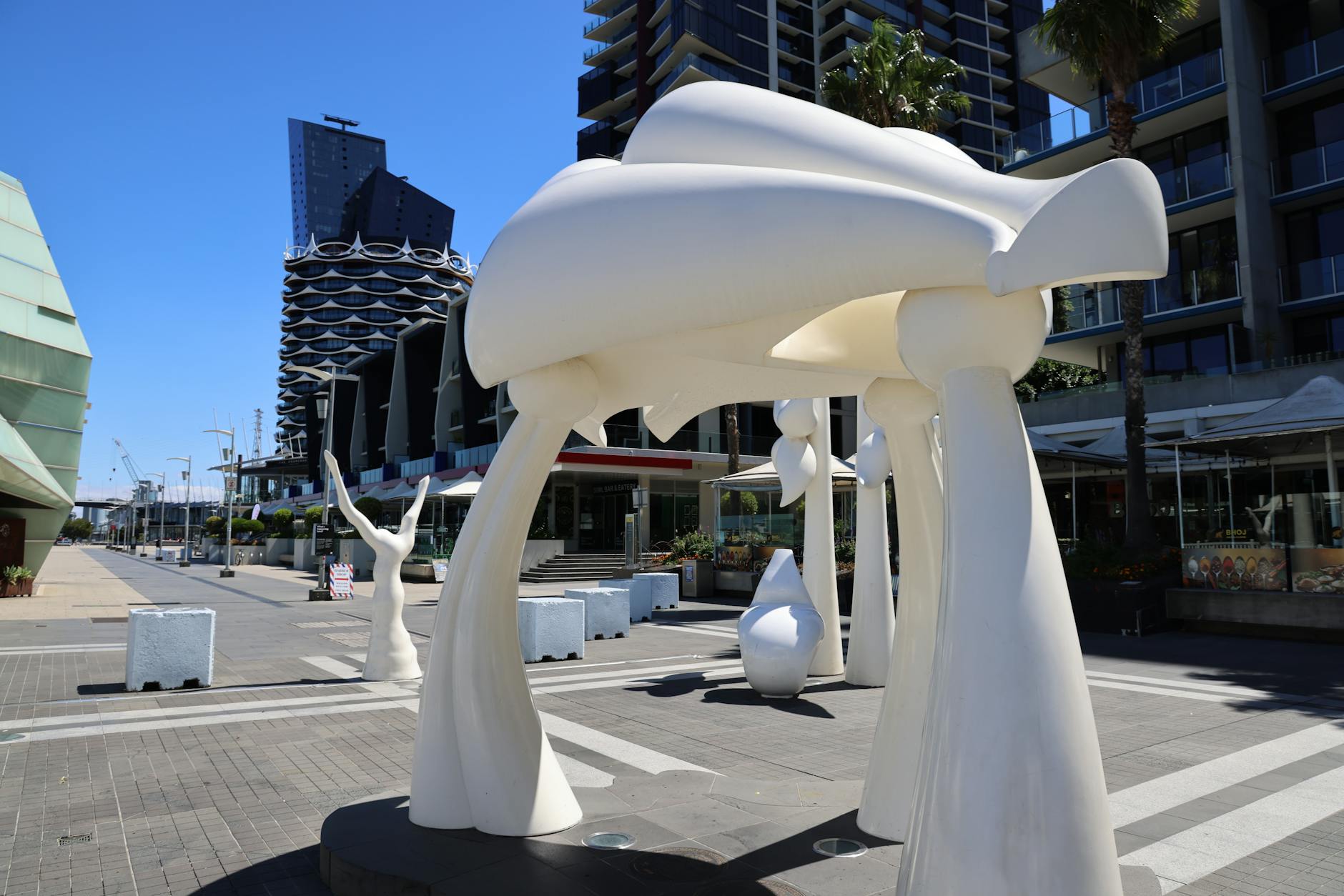 Abstract sculptures set against modern urban architecture on a sunny day, showcasing artistic design.