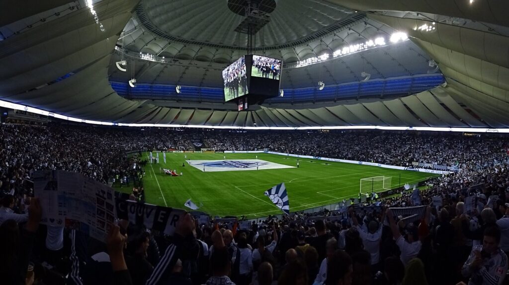Crowd and pitch inside BC Place during a soccer match with the roof lights above
