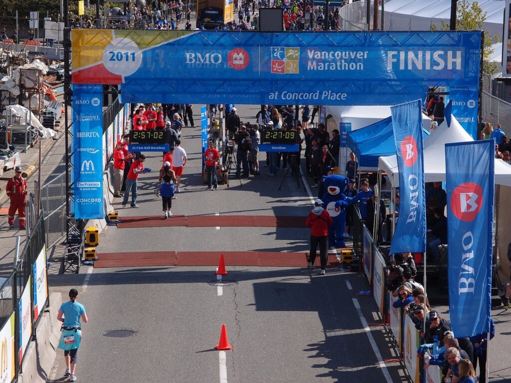 Runners approaching the finish arch of the BMO Vancouver Marathon with spectators behind barriers