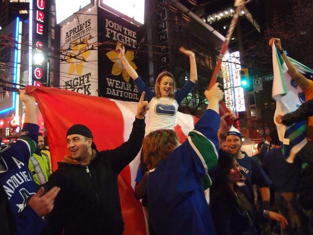 Canucks fans waving flags and a Canadian flag on a downtown street at night