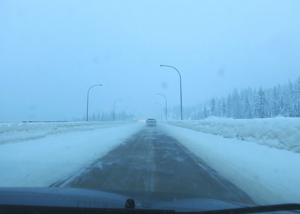 Snow-covered lanes and poor visibility on the Coquihalla Highway in winter, a reminder for road trips from Vancouver