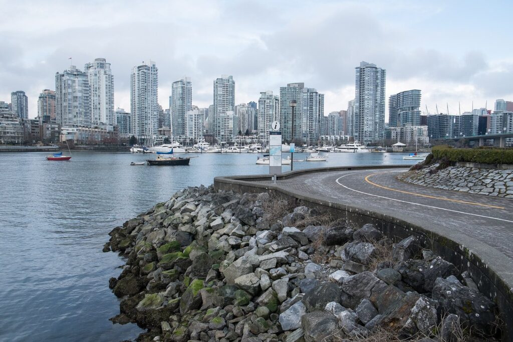 The False Creek seawall curving past a rock breakwater with Yaletown towers across the water