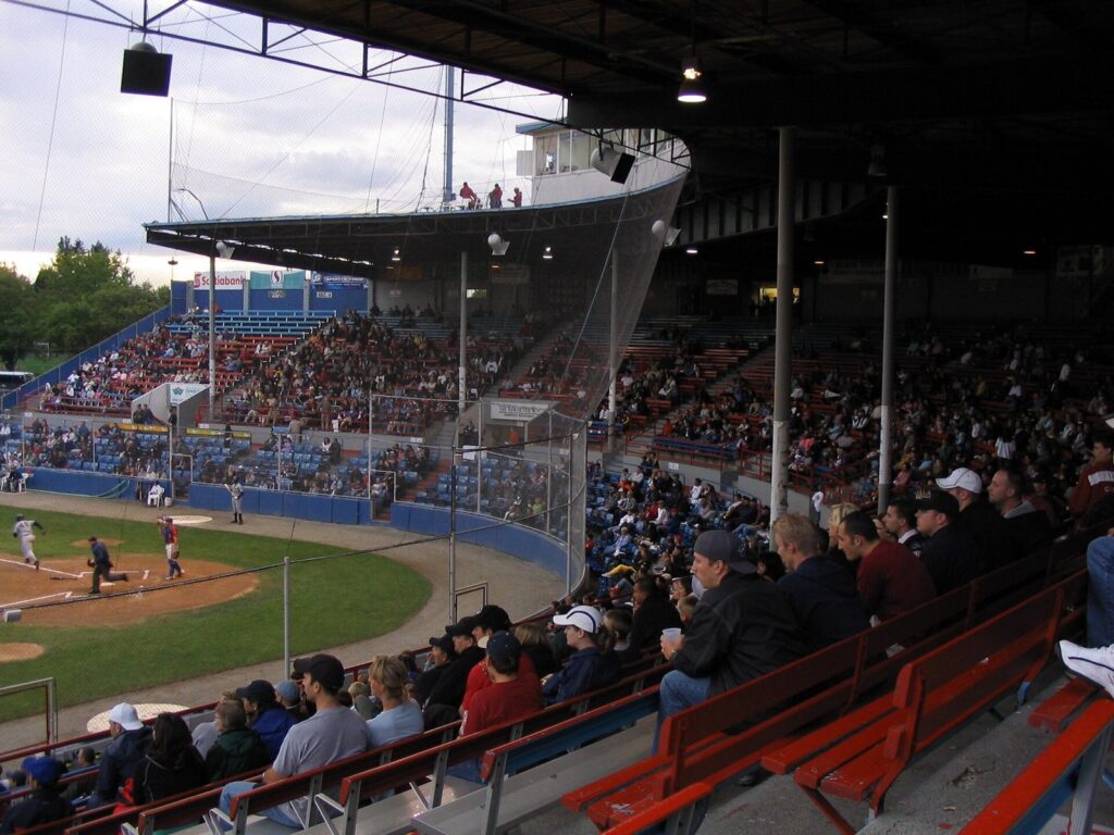 Fans in the covered grandstand at Nat Bailey Stadium watching a game under the roof