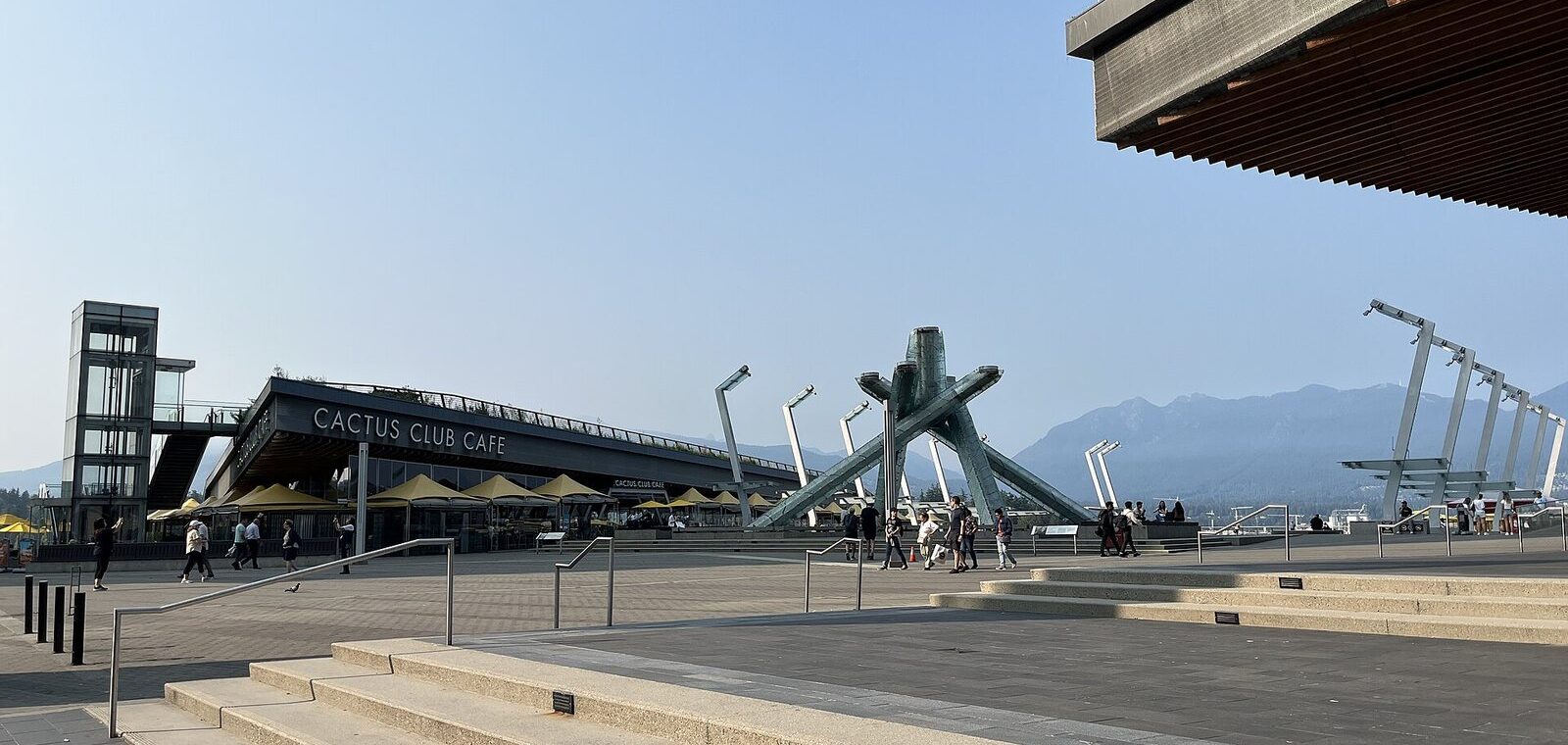 The white 2010 Olympic Cauldron on Jack Poole Plaza with the Coal Harbour waterfront and mountains behind