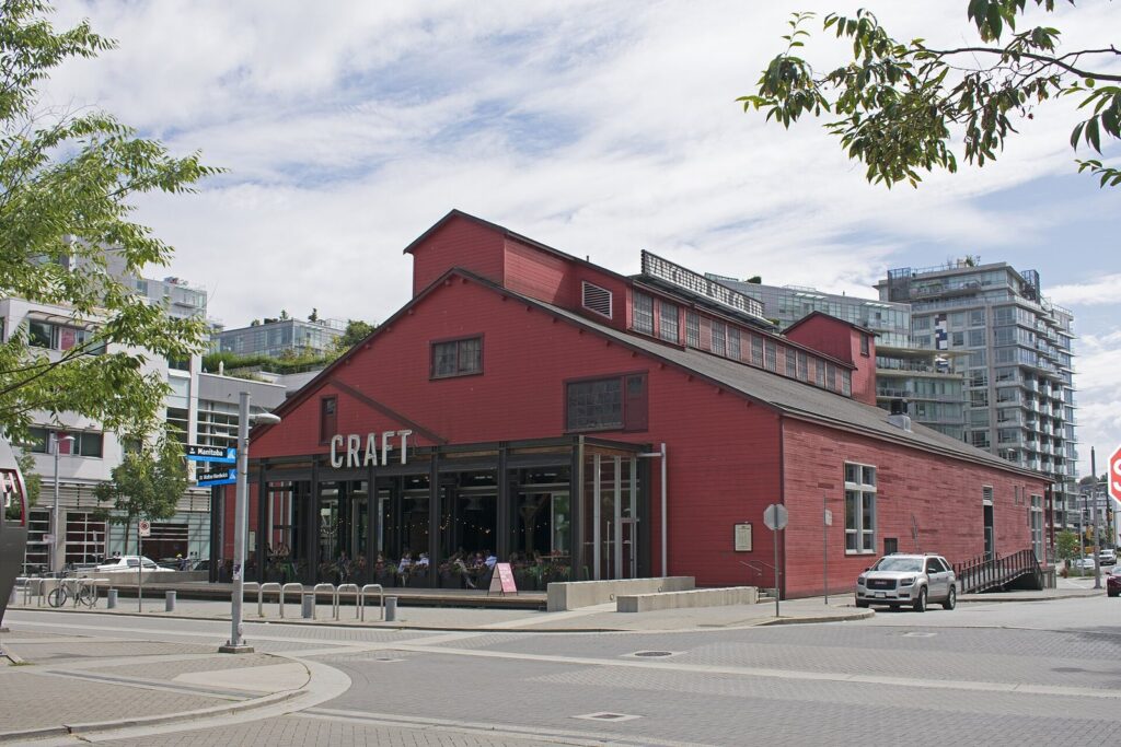 The red wooden Salt Building in Olympic Village with the CRAFT Beer Market sign on its side