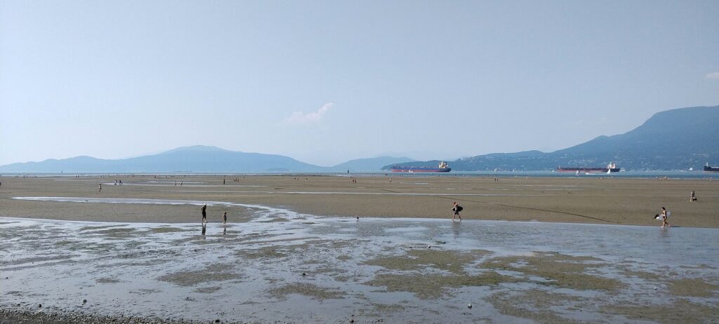 Wide tidal flats at Spanish Banks with the North Shore mountains and anchored ships beyond