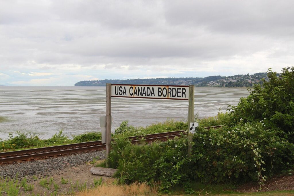 USA Canada Border sign beside the railway tracks at Semiahmoo Bay near Peace Arch Park