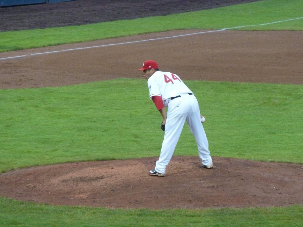 Vancouver Canadians pitcher in a white and red uniform leaning in for a sign on the Nat Bailey mound