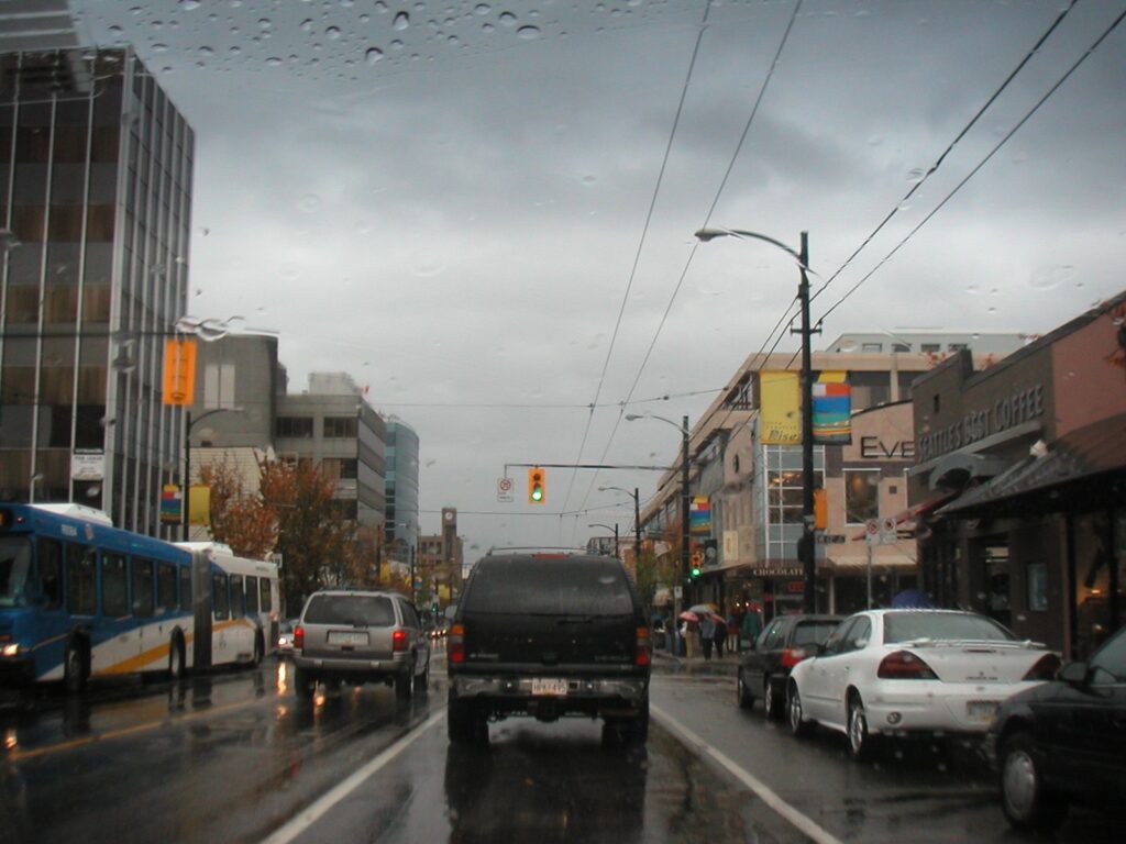 Rainy Vancouver street with trolleybus wires and wet traffic, the weather behind most Vancouver travel tips
