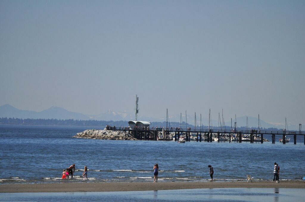 White Rock pier stretching over Semiahmoo Bay with people on the beach in front