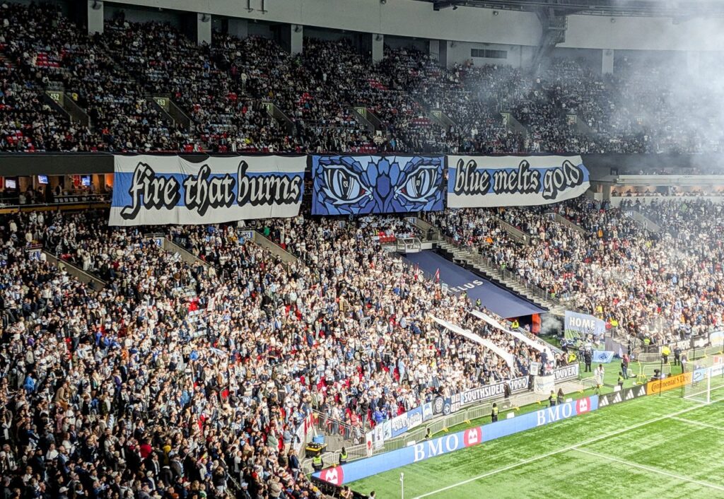 Supporters at BC Place unfurling a giant Fire That Burns banner, the section to buy Whitecaps tickets in if you want to stand and sing