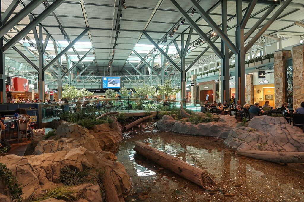 Skylit interior of the Vancouver International Airport international terminal with a landscaped creek and rocks